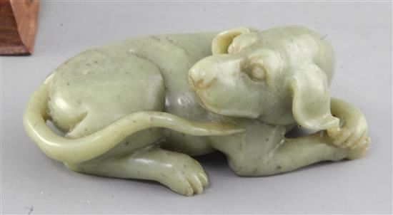 A Chinese green jade figure of a recumbent dog, length 12.5cm excl. wood stand